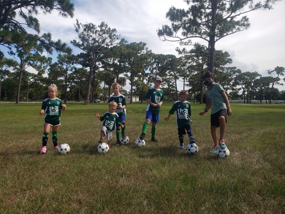children participating in soccer for success pose for a photo wearing their green jerseys