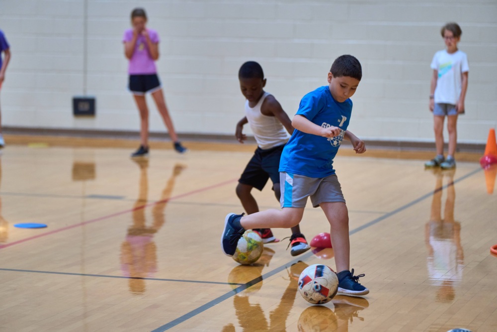 Boys playing soccer in a gym