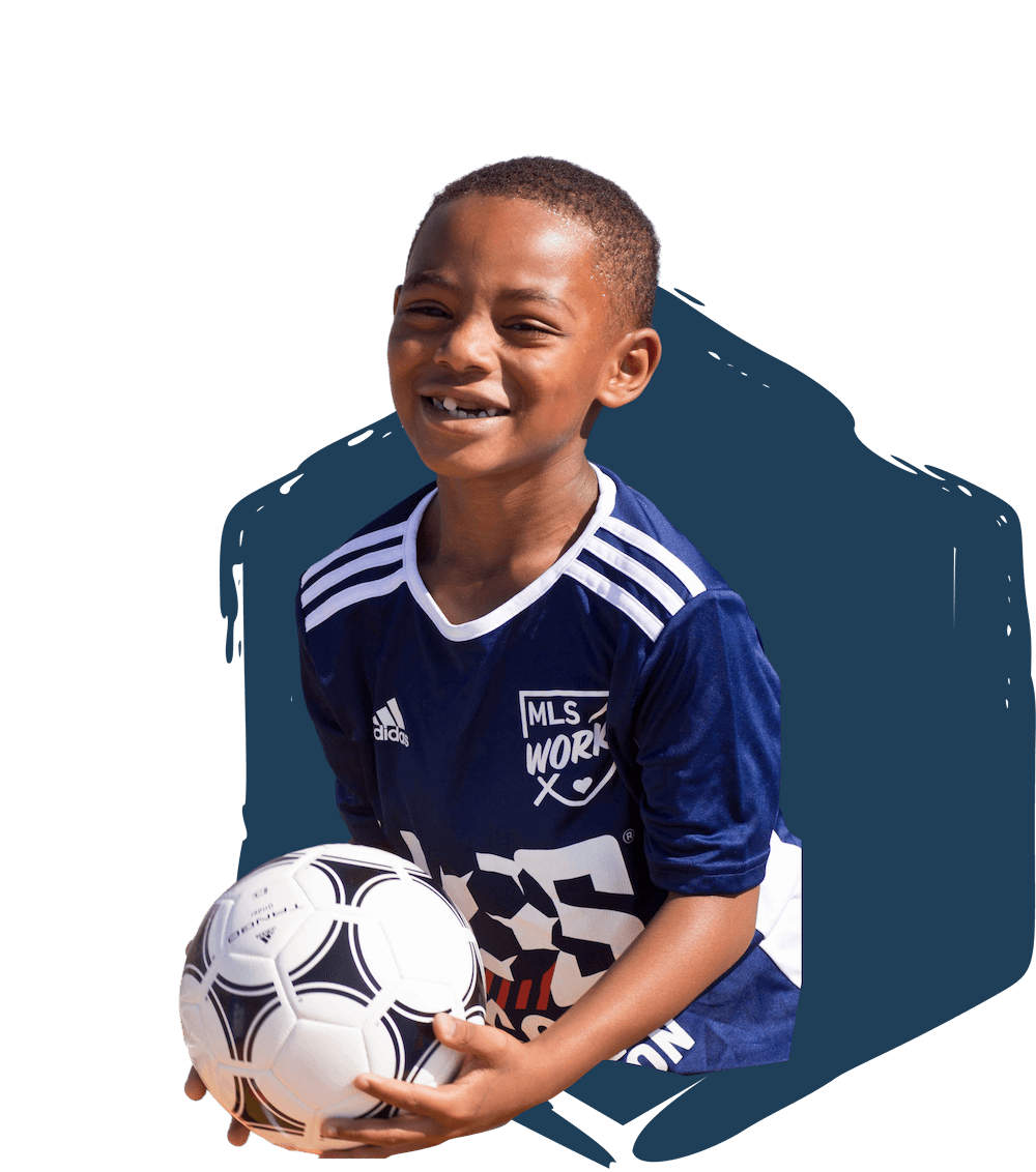 boy smiling while holding a soccer ball