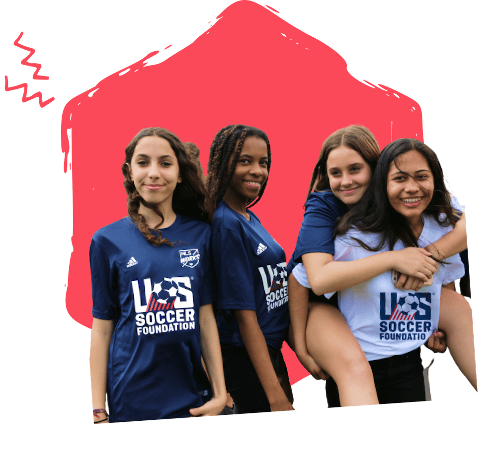 four girls in soccer jerseys smiling