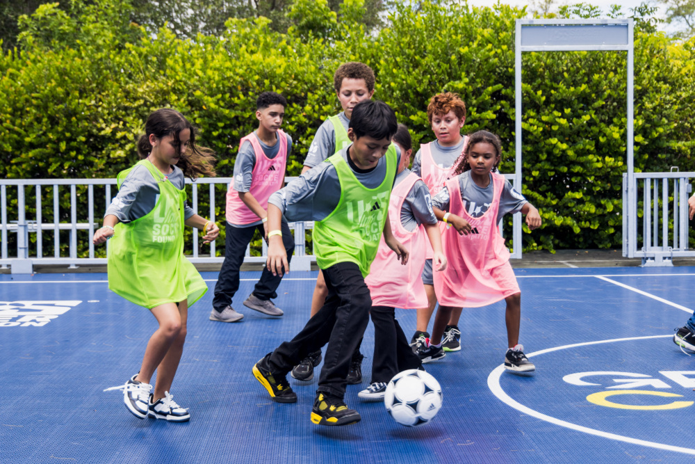 Kids play first game on mini-pitch in green and pink pinnies