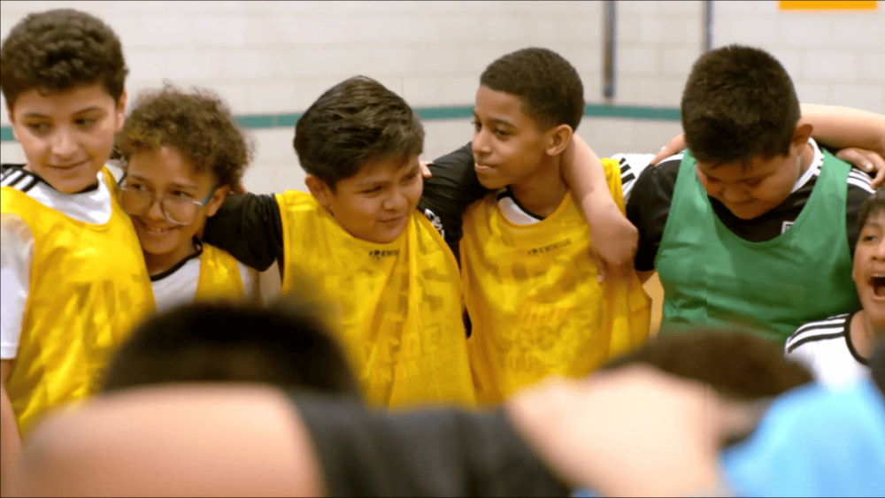 Boys in yellow jerseys pose in circle