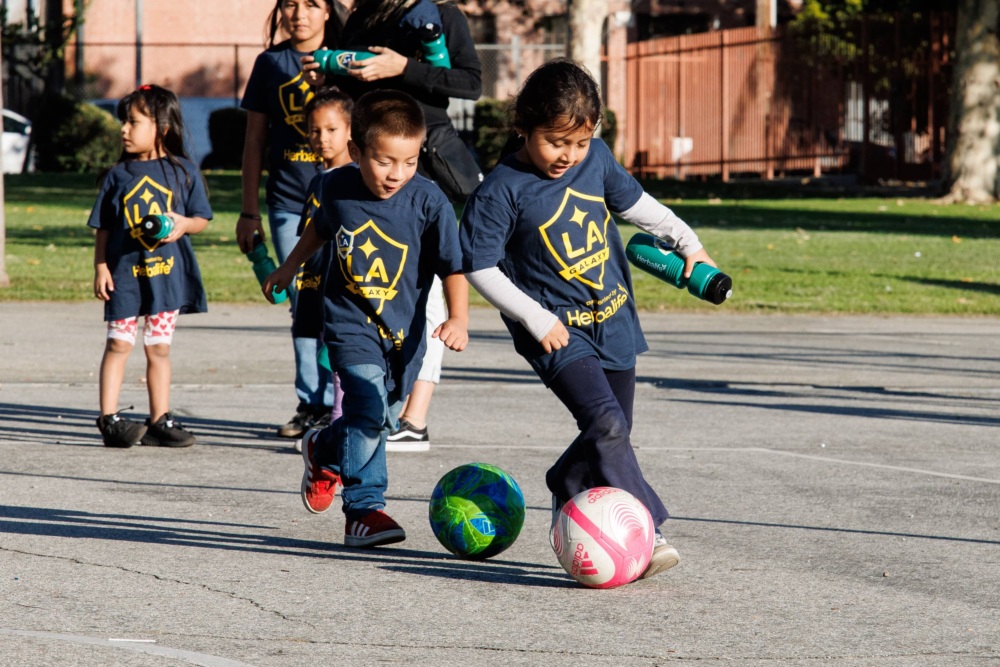Girl and Boy kicking two soccer balls
