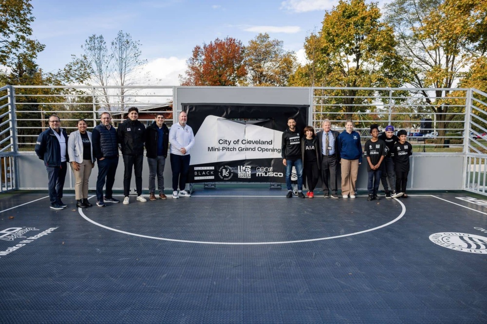Group poses in front of banner reading "City of Cleveland Mini-pitch grand opening"