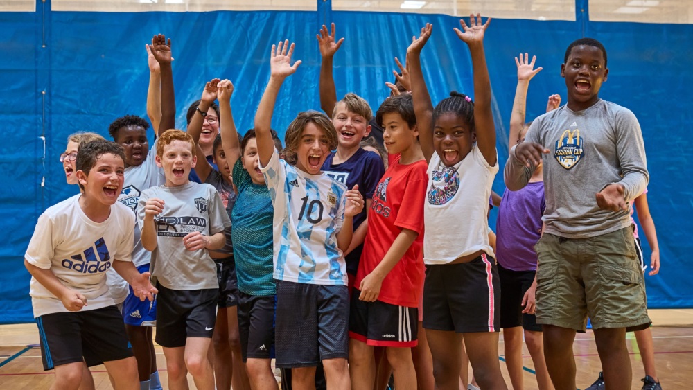 Kids with hands in the air smiling and shouting