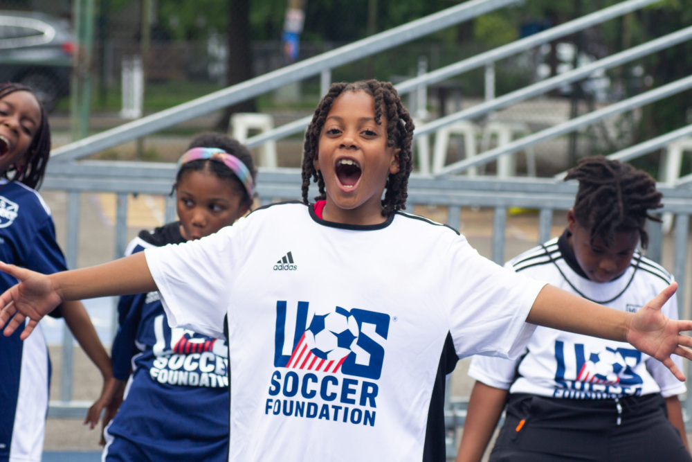 Kid standing on mini-pitch and shouting excited with arms outstretched