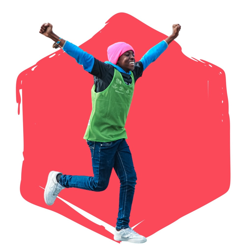 Boy running, arms in the arm and smiling in front of a red hexagon