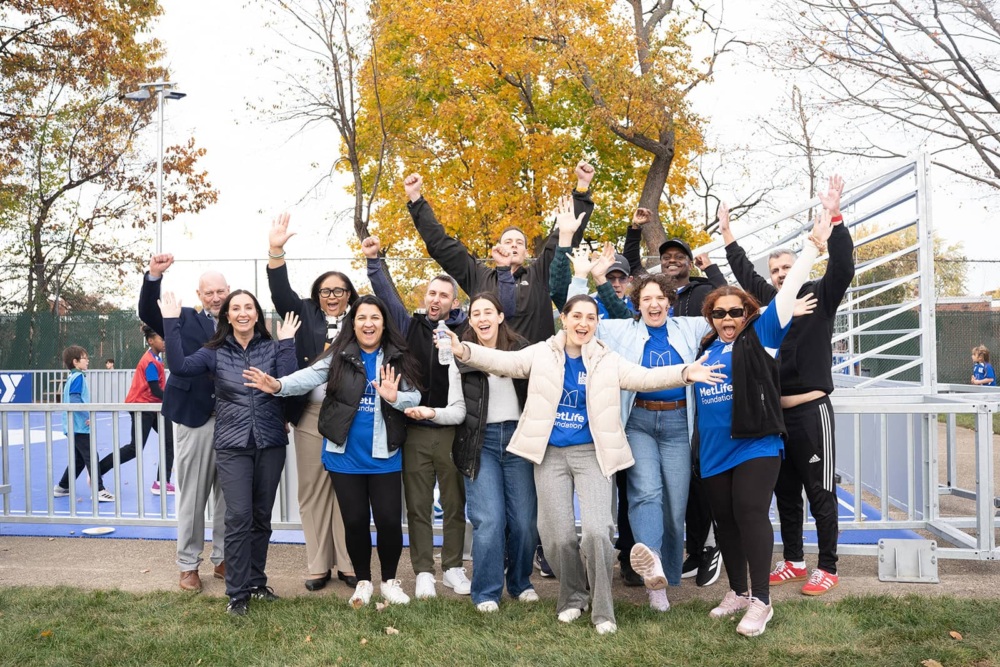 Adults cheer in front of new mini-pitch opened through MetLife & US Soccer Foundation partnership