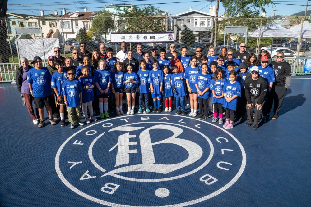 Youth athletes, partners, and community members pose on new mini-pitch