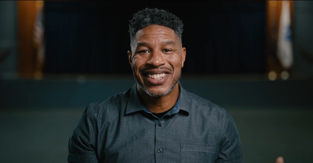 Man in dark blue button up shirt smiling at camera